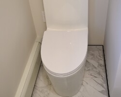 One peace toilet with power outlet next to it.