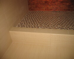 Step to shower covered with ceramic tiles.