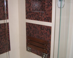 Folding bench inside the steam shower. Glass mosaic on the walls.