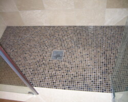 Glass mosaic shower floor with square grill.